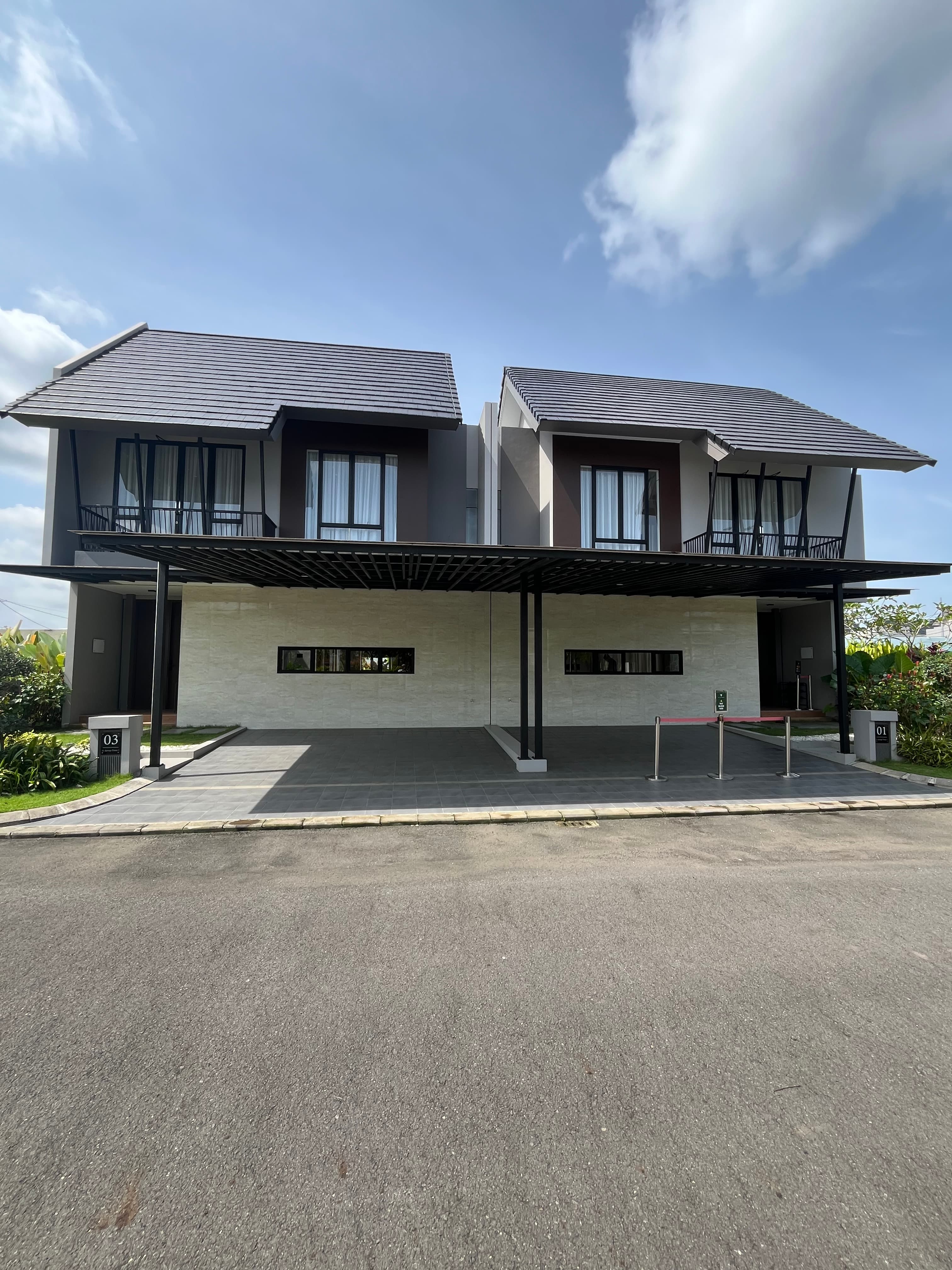 Modern two-story duplex featuring dark tiled roofs, cream walls, and large black-framed windows.